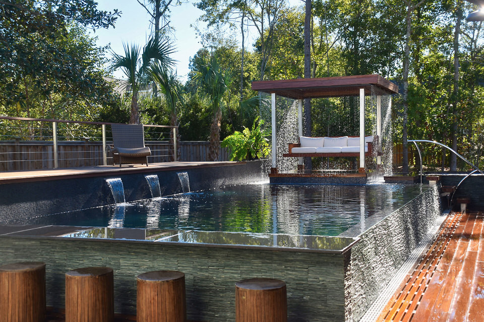 Imagen de piscina con fuente infinita exótica grande rectangular en patio lateral con entablado