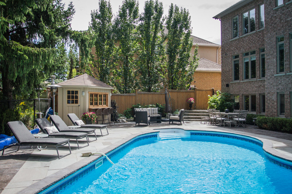 Medium sized contemporary back round lengths swimming pool in Toronto with natural stone paving and a pool house.