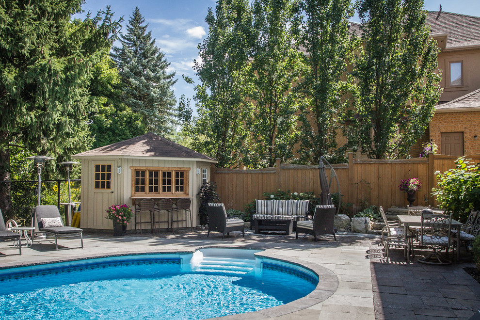 Foto di una piscina monocorsia design rotonda dietro casa e di medie dimensioni con pavimentazioni in pietra naturale e una dépendance a bordo piscina
