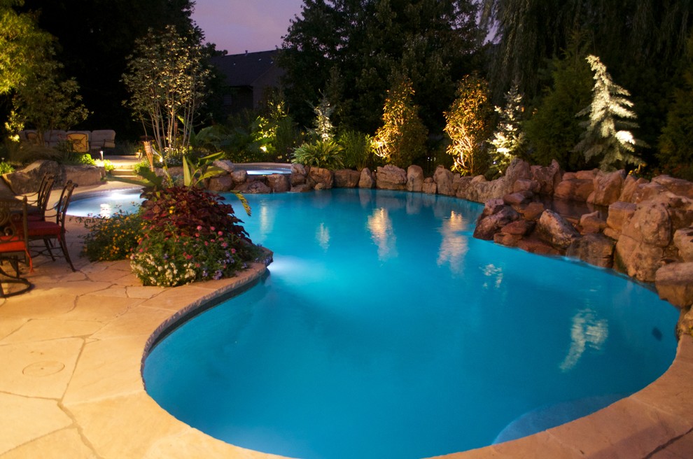 Imagen de piscina con fuente rústica de tamaño medio a medida en patio trasero con adoquines de piedra natural
