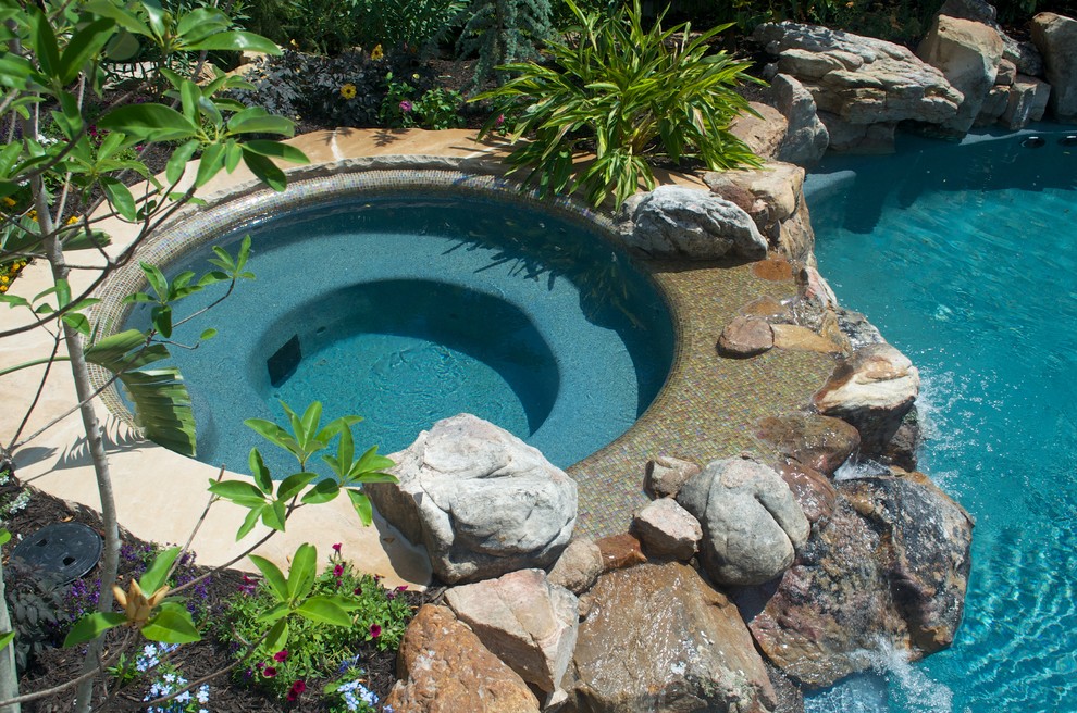 Inspiration for a large rustic back custom shaped hot tub in Kansas City with natural stone paving.