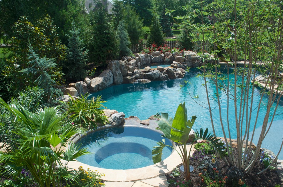 Cette photo montre une grande piscine arrière montagne sur mesure avec des pavés en pierre naturelle et un bain bouillonnant.