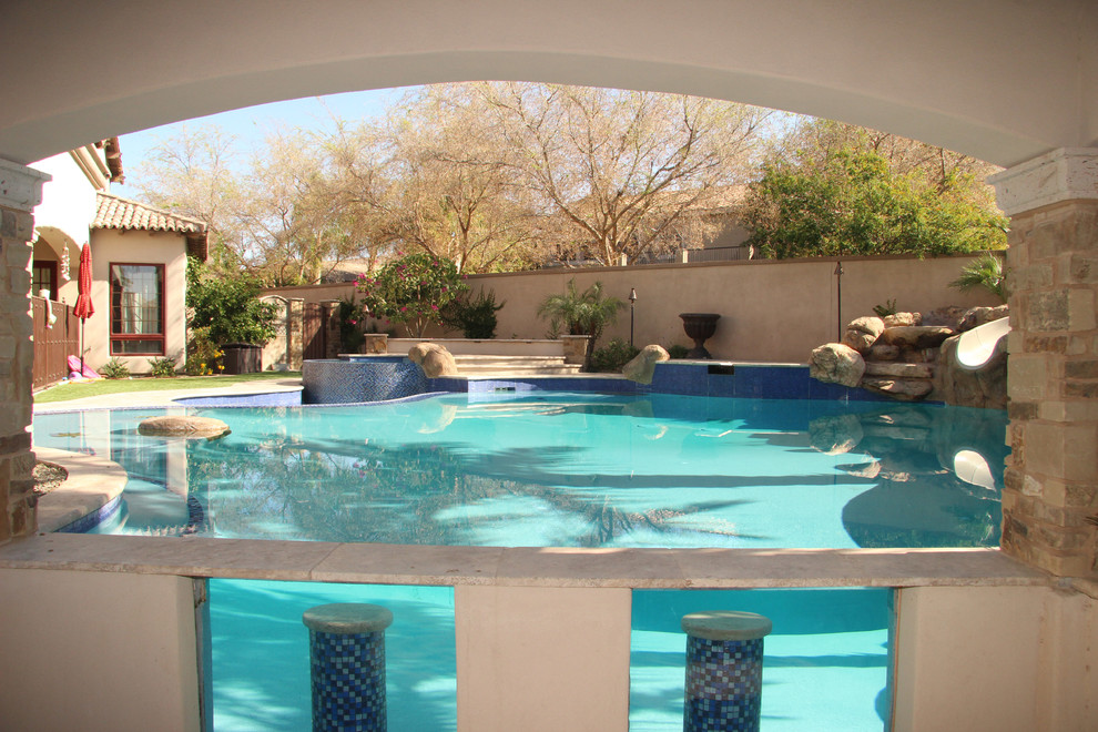 Immagine di una grande piscina naturale mediterranea personalizzata dietro casa con pavimentazioni in pietra naturale