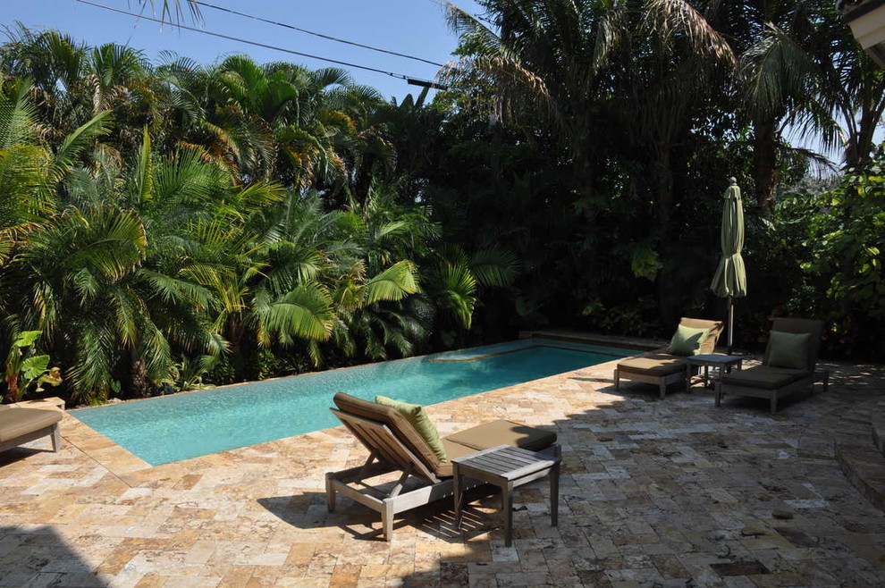 Modelo de piscina infinita mediterránea de tamaño medio rectangular en patio trasero con adoquines de piedra natural