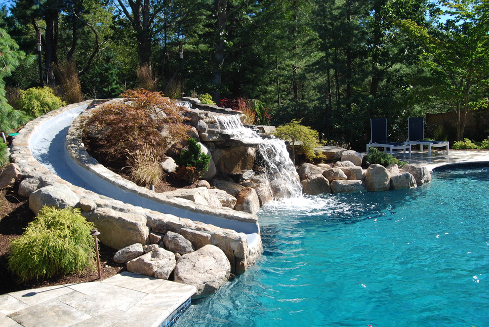 Diseño de piscina con tobogán natural rural de tamaño medio tipo riñón en patio trasero con adoquines de piedra natural