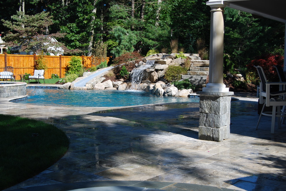 Réalisation d'une piscine naturelle et arrière chalet en forme de haricot de taille moyenne avec un toboggan et des pavés en pierre naturelle.