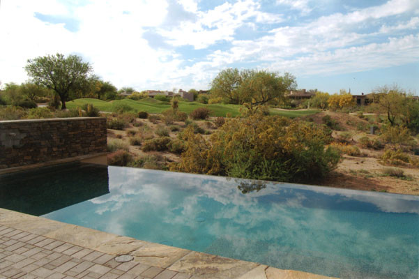 Diseño de piscinas y jacuzzis naturales tropicales extra grandes tipo riñón en patio trasero con adoquines de piedra natural