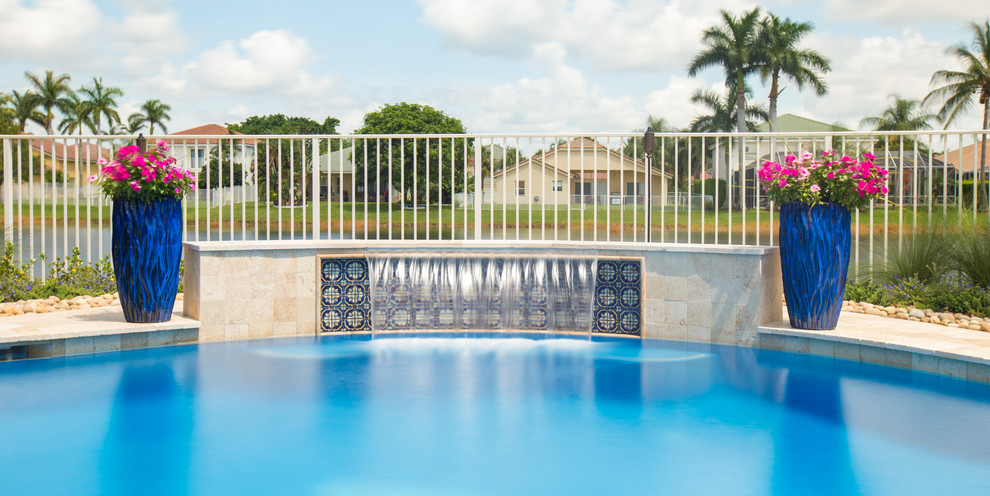 Mittelgroßer Moderner Schwimmteich hinter dem Haus in individueller Form mit Wasserspiel und Natursteinplatten in Miami