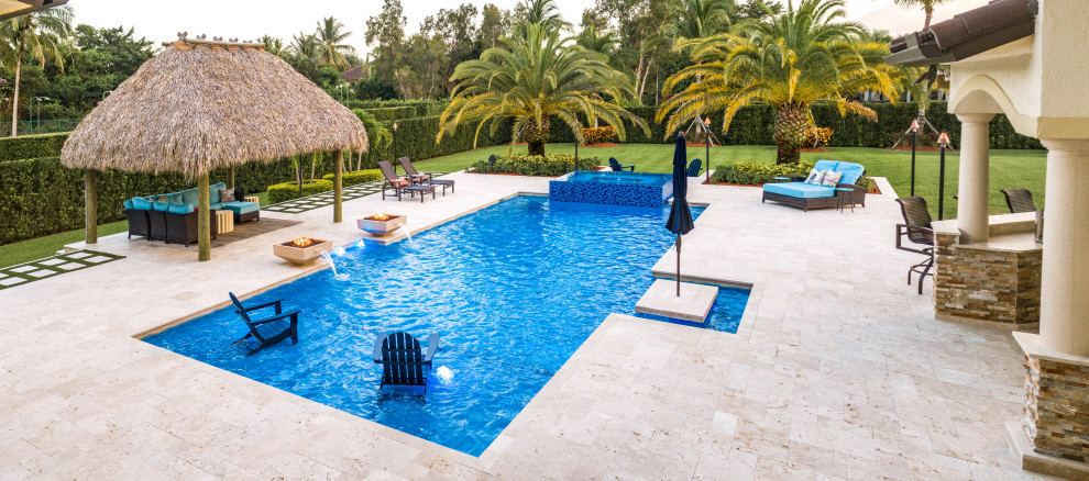 Geräumiges Sportbecken hinter dem Haus in individueller Form mit Wasserspiel und Natursteinplatten in Miami