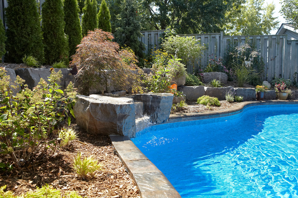 Ejemplo de piscina con fuente natural contemporánea grande a medida en patio trasero con adoquines de ladrillo