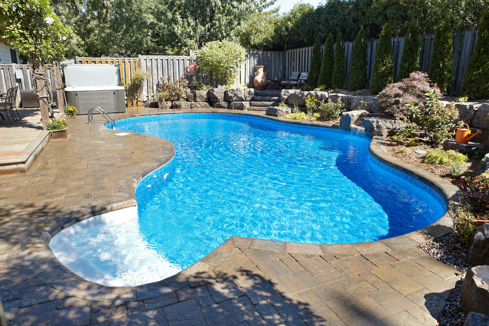 Aménagement d'une grande piscine naturelle et arrière contemporaine sur mesure avec un point d'eau et des pavés en brique.