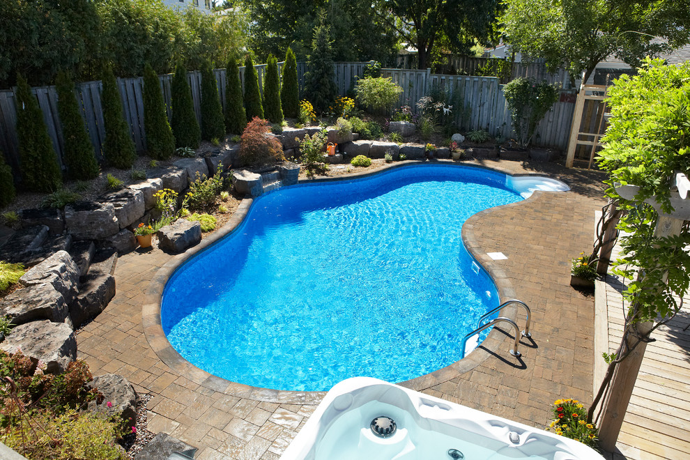 На фото: большой естественный бассейн произвольной формы на заднем дворе в современном стиле с фонтаном и мощением клинкерной брусчаткой с
