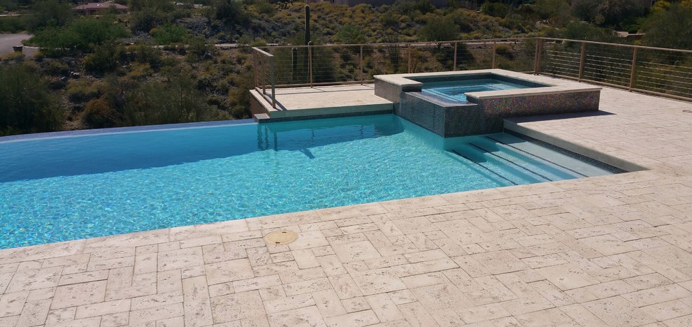 Idées déco pour une piscine à débordement et arrière contemporaine rectangle avec un bain bouillonnant et des pavés en béton.