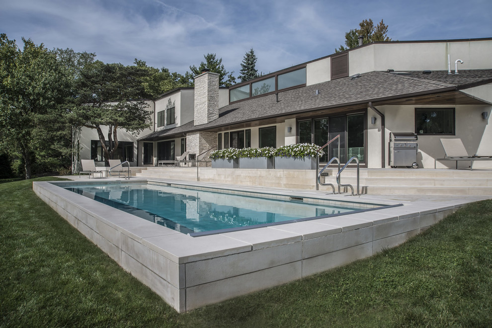 Diseño de piscina minimalista de tamaño medio rectangular en patio trasero con adoquines de piedra natural