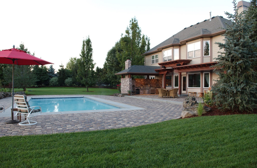 Ejemplo de piscina natural tradicional grande rectangular en patio trasero con adoquines de hormigón
