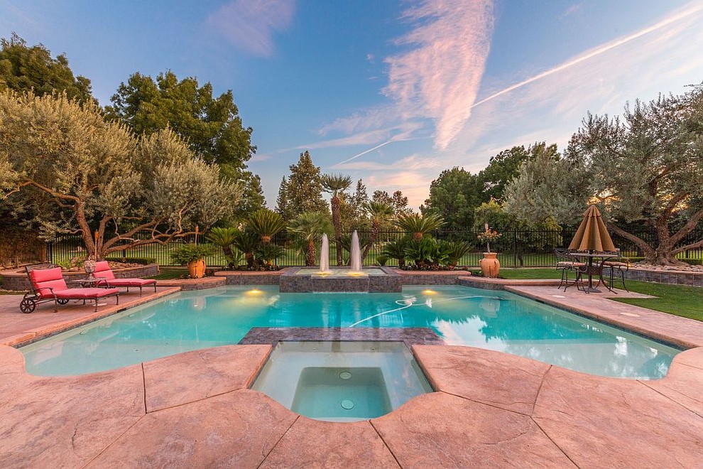 Ejemplo de piscina con fuente mediterránea grande a medida en patio trasero con suelo de hormigón estampado