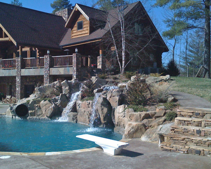 Photo of a large rustic back custom shaped swimming pool in Charlotte with natural stone paving and a water slide.