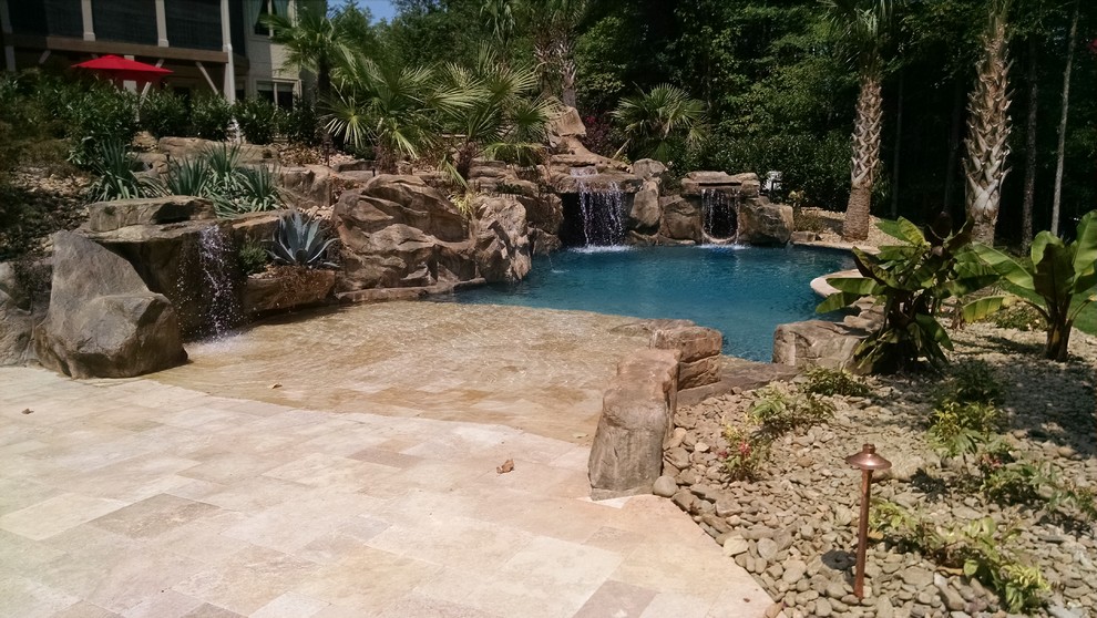 Modelo de piscina con tobogán mediterránea grande a medida en patio trasero con adoquines de piedra natural