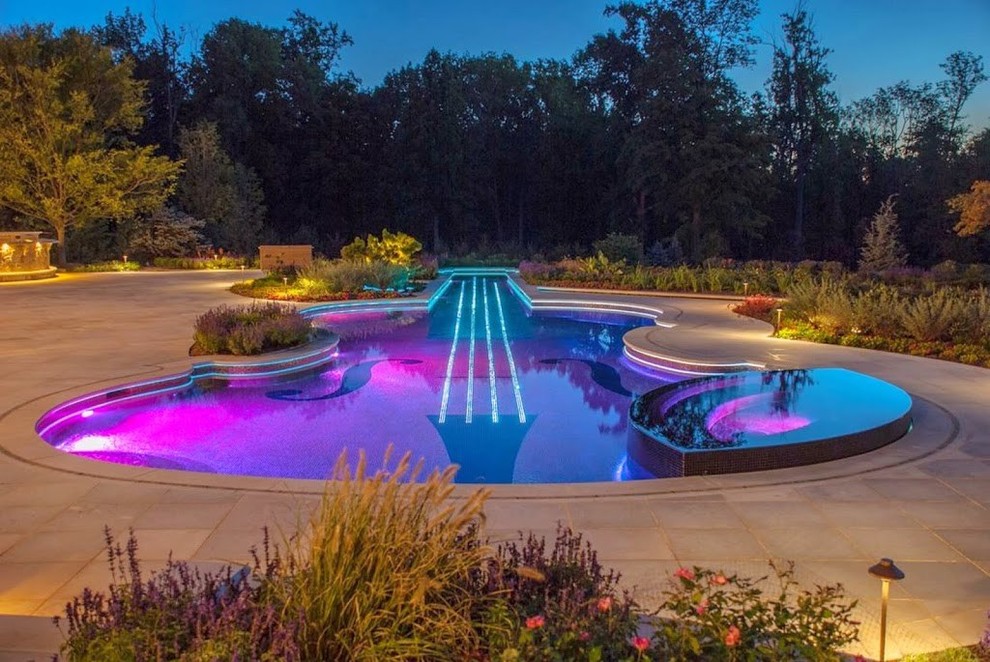 Immagine di una grande piscina naturale contemporanea personalizzata dietro casa con una vasca idromassaggio e pavimentazioni in pietra naturale