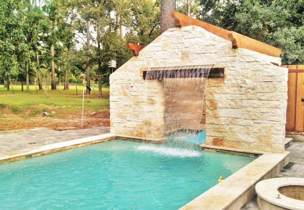 Rustik inredning av en mellanstor rektangulär pool på baksidan av huset, med en fontän och naturstensplattor