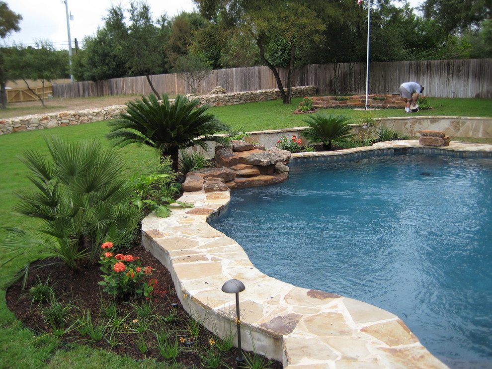 Ejemplo de piscina con fuente alargada clásica grande a medida en patio trasero con adoquines de piedra natural