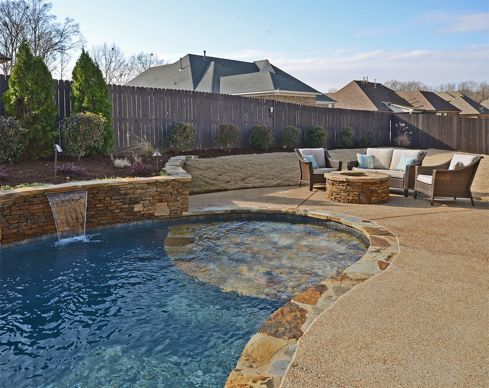 Modelo de piscina con fuente alargada exótica grande a medida en patio trasero con losas de hormigón
