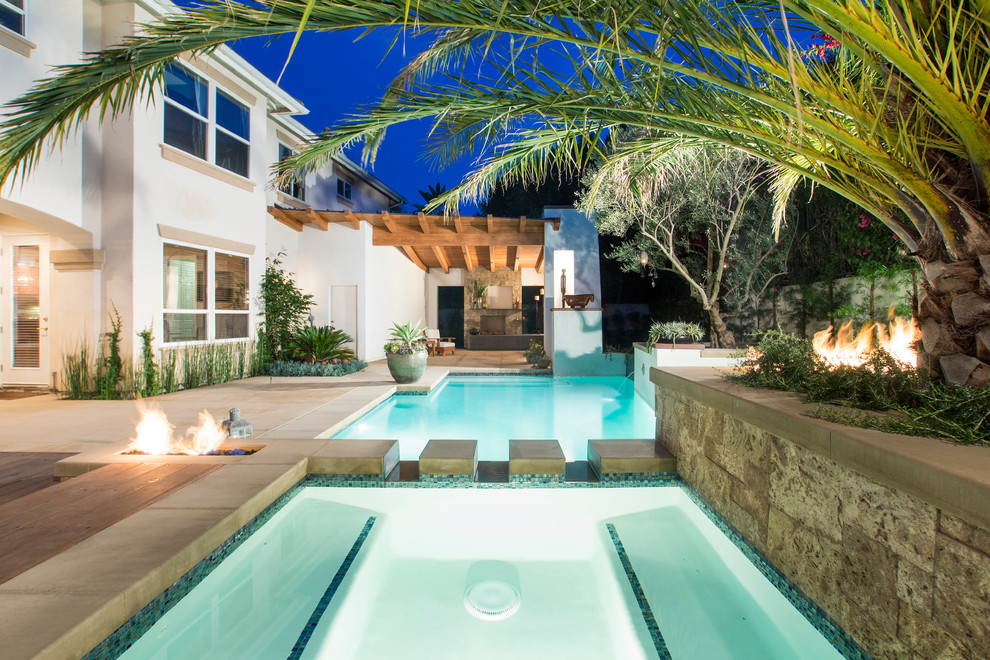 Ispirazione per una piscina tropicale personalizzata di medie dimensioni e dietro casa con lastre di cemento