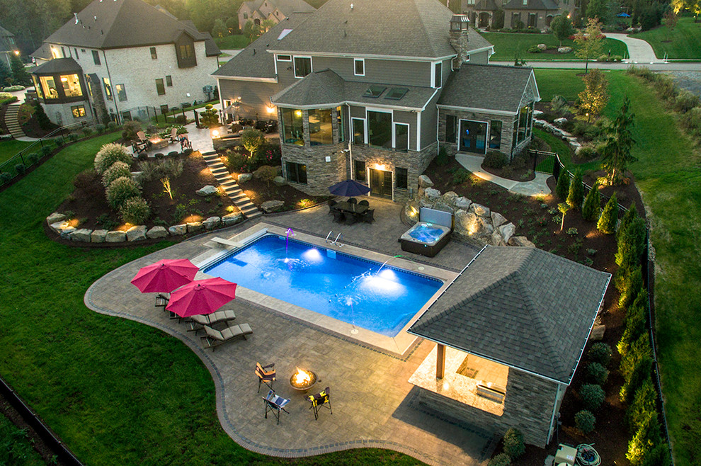 Ejemplo de piscinas y jacuzzis actuales de tamaño medio rectangulares en patio trasero con adoquines de ladrillo