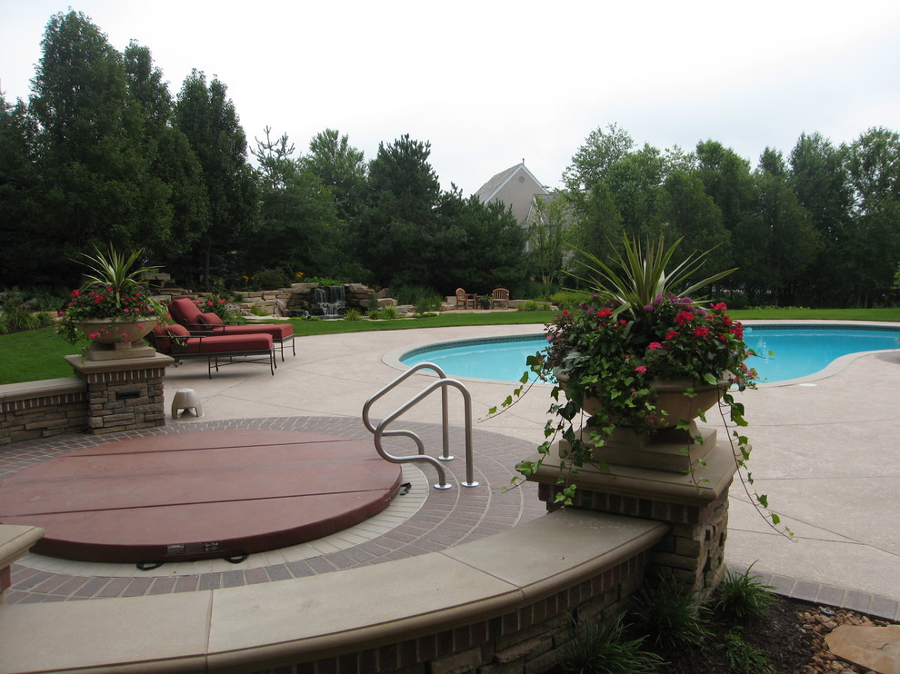 Ejemplo de piscinas y jacuzzis clásicos renovados grandes a medida en patio trasero con adoquines de ladrillo