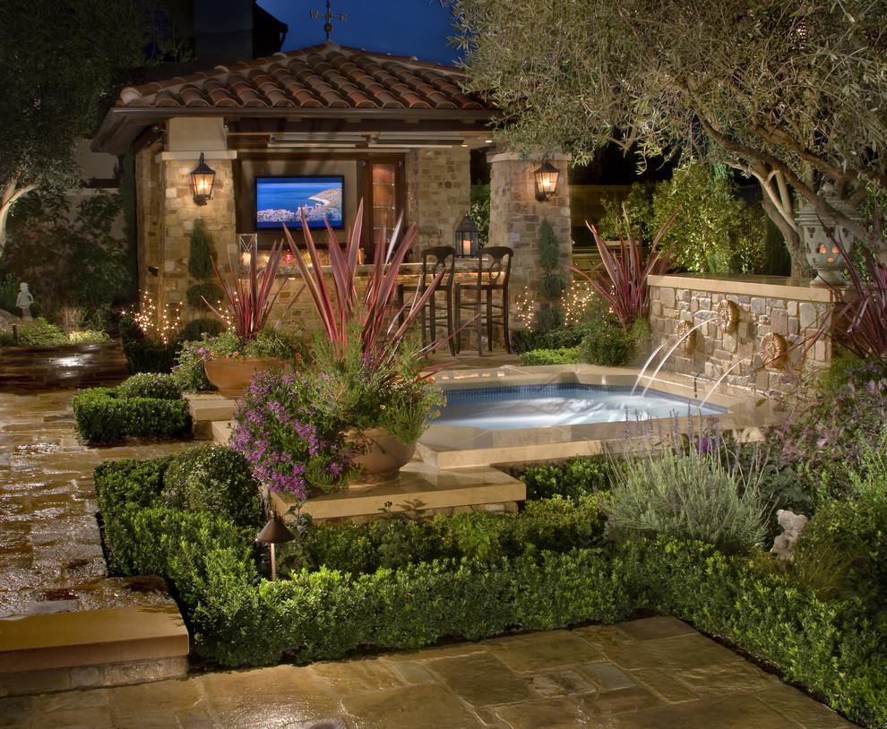 Inspiration for a small rustic back custom shaped hot tub in Los Angeles with natural stone paving.