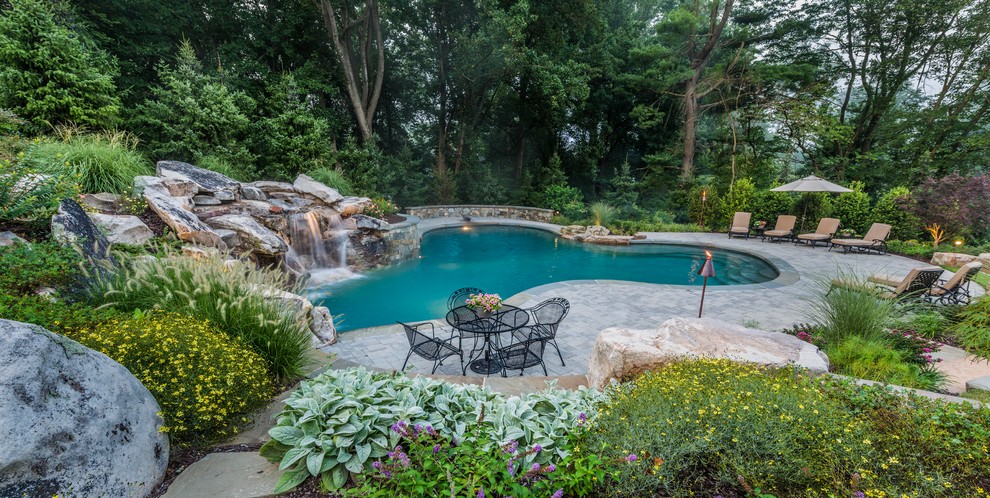 Photo of a medium sized rustic back custom shaped lengths swimming pool in DC Metro with a water feature and concrete paving.