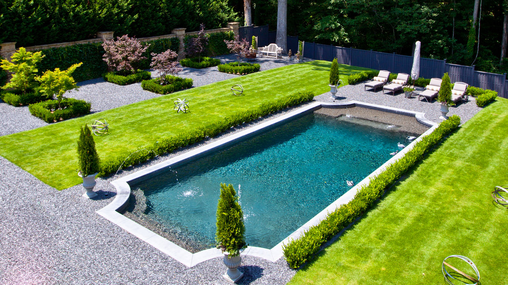 На фото: прямоугольный бассейн в классическом стиле с покрытием из гравия и забором с