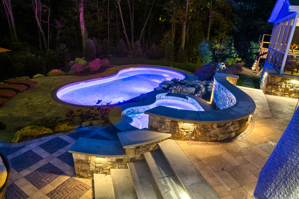 Idée de décoration pour une piscine arrière tradition en forme de haricot de taille moyenne avec un bain bouillonnant et des pavés en pierre naturelle.
