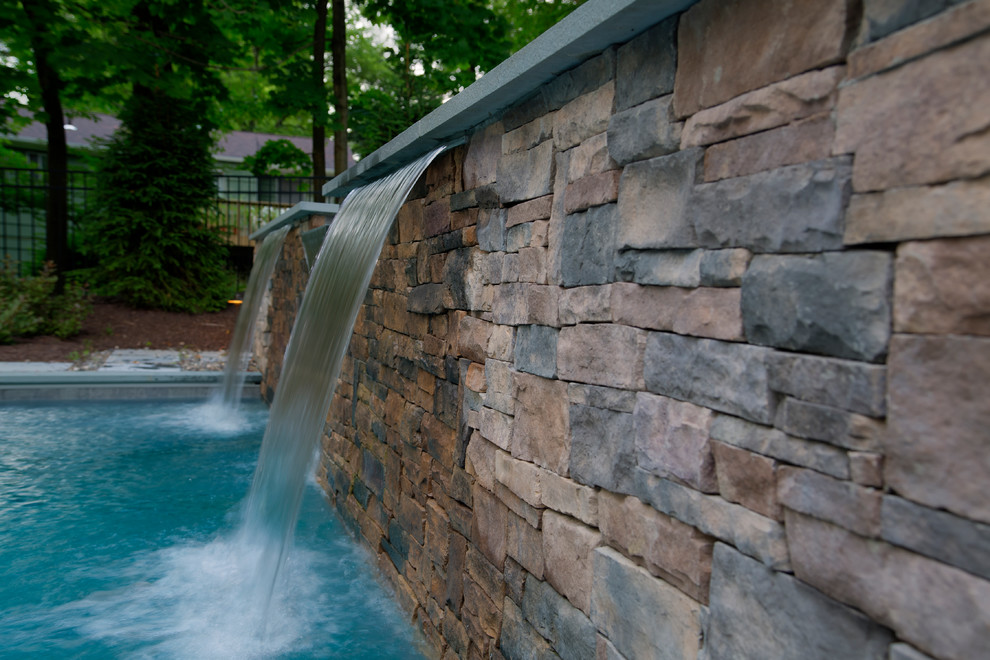 Ispirazione per una piscina moderna rettangolare di medie dimensioni e dietro casa con fontane e pavimentazioni in pietra naturale