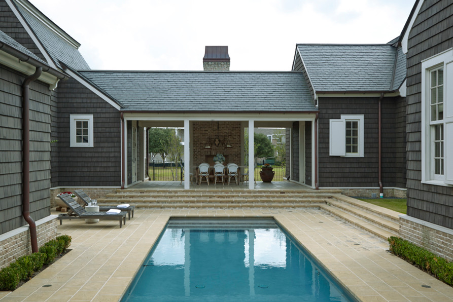 Immagine di una grande piscina costiera rettangolare dietro casa con pavimentazioni in pietra naturale