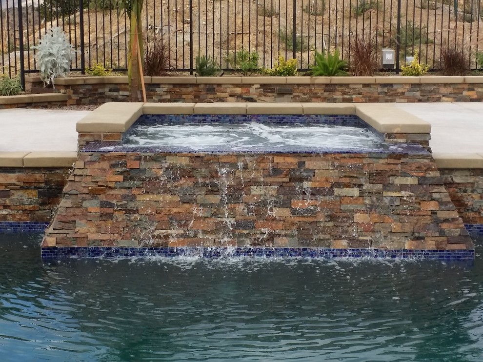 Esempio di una grande piscina classica rettangolare dietro casa con cemento stampato e una vasca idromassaggio