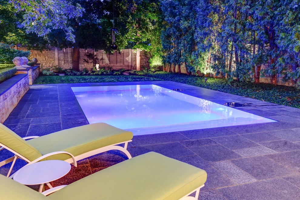 Modelo de piscina infinita clásica pequeña rectangular en patio trasero con adoquines de piedra natural
