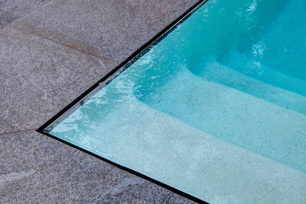 Esempio di una piccola piscina a sfioro infinito tradizionale rettangolare dietro casa con pavimentazioni in pietra naturale