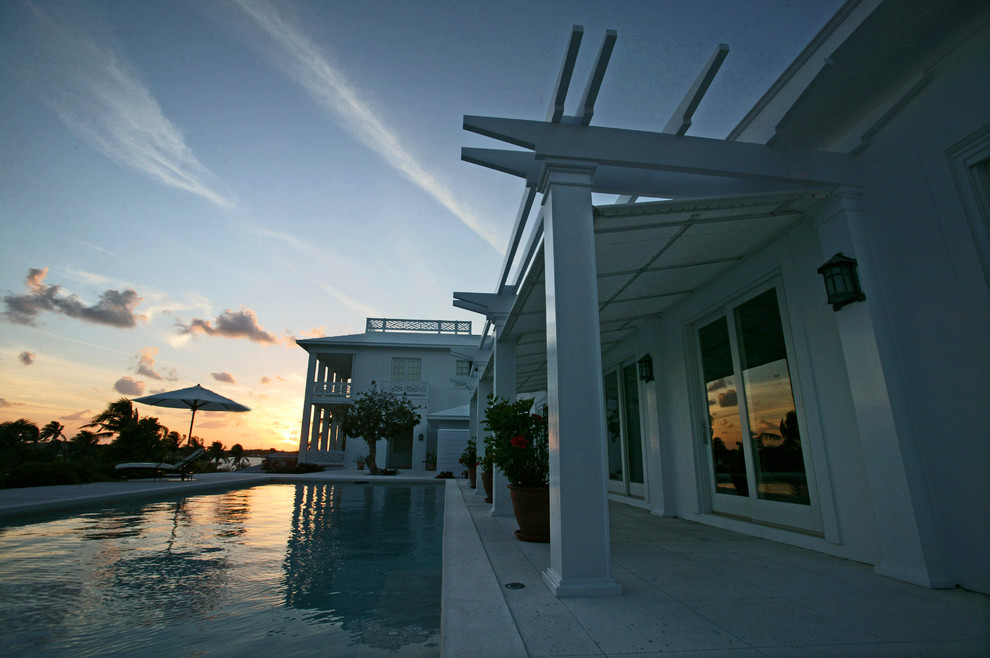 Modelo de casa de la piscina y piscina alargada exótica de tamaño medio rectangular en patio trasero con adoquines de hormigón