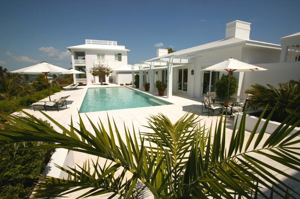 Diseño de casa de la piscina y piscina alargada tropical de tamaño medio rectangular en patio trasero con adoquines de hormigón