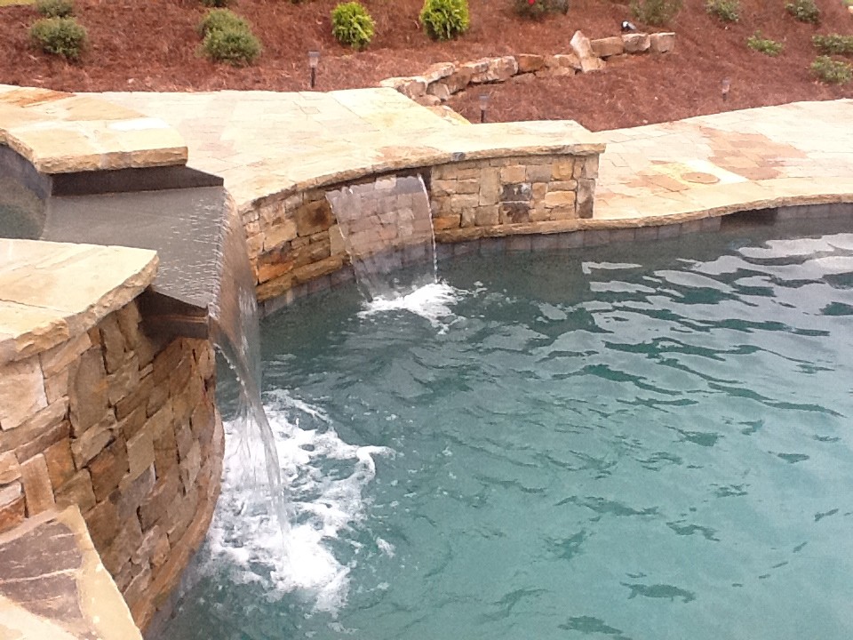 Foto de piscina con fuente natural rústica grande a medida en patio trasero con adoquines de piedra natural