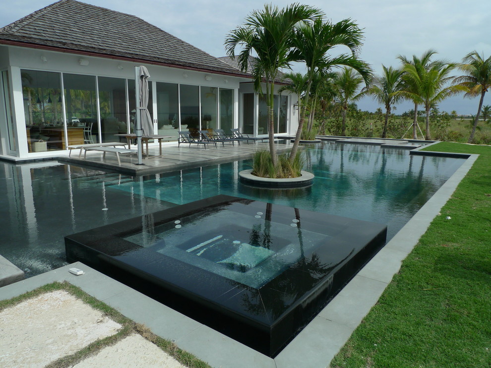 Inspiration for an expansive coastal back rectangular hot tub in Miami with natural stone paving.
