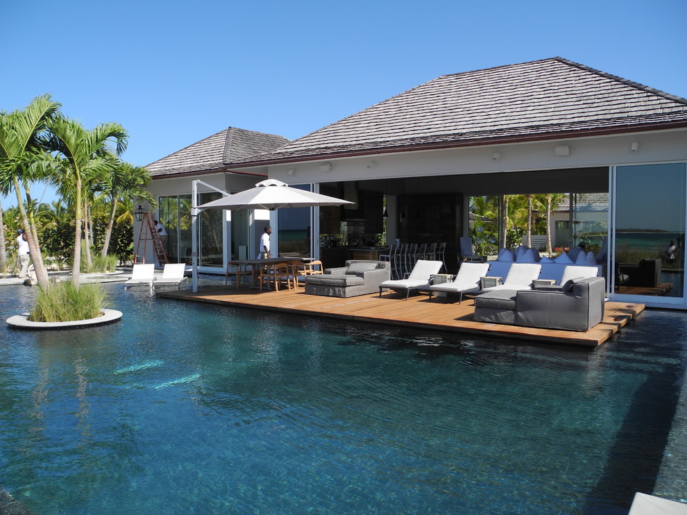Modelo de piscinas y jacuzzis costeros extra grandes rectangulares en patio trasero con adoquines de piedra natural