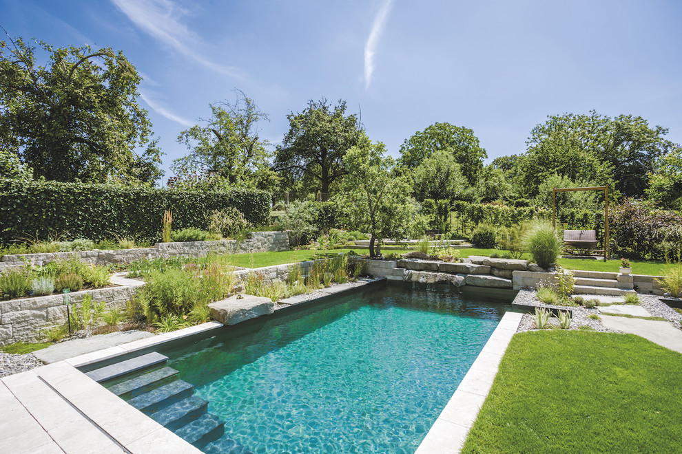 Inspiration for a large contemporary back rectangular swimming pool in Munich with natural stone paving.