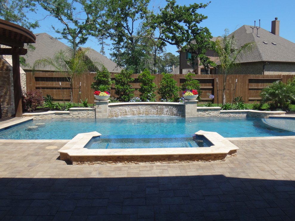 Imagen de piscina con fuente alargada tradicional grande a medida en patio trasero con adoquines de ladrillo