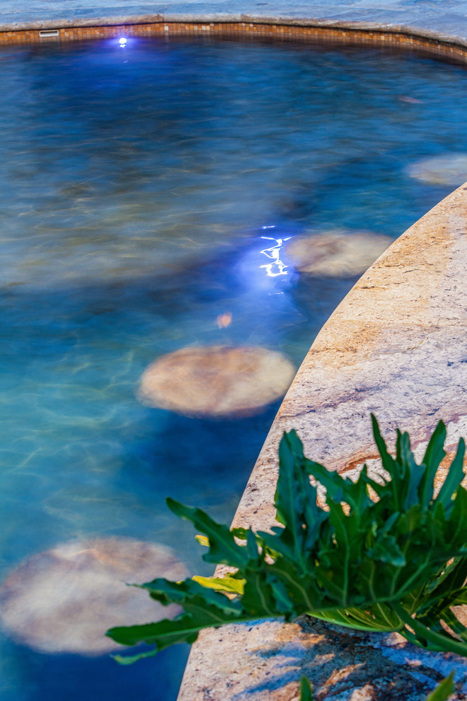 Cette image montre une piscine naturelle et arrière ethnique de taille moyenne et sur mesure avec un point d'eau et des pavés en pierre naturelle.