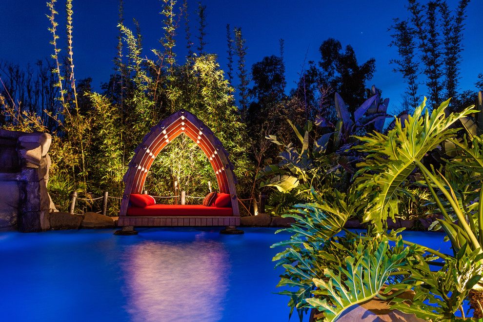 Idee per un'ampia piscina naturale tropicale personalizzata dietro casa con pavimentazioni in pietra naturale