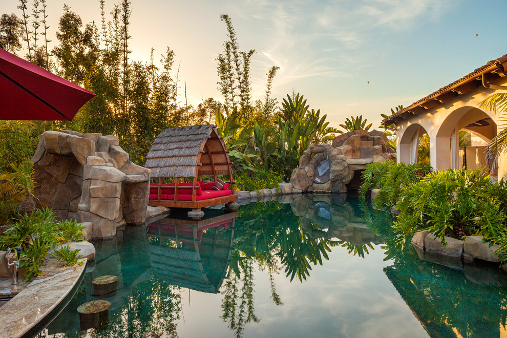 Foto de piscina natural tropical extra grande a medida en patio trasero con adoquines de piedra natural