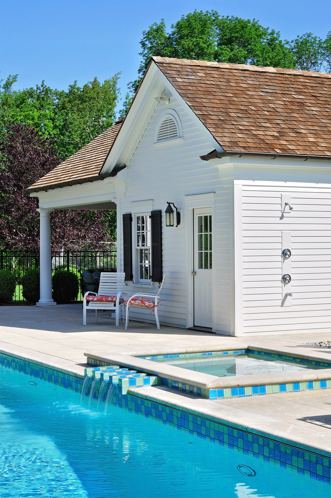 Modelo de casa de la piscina y piscina alargada tradicional grande rectangular en patio trasero con adoquines de hormigón