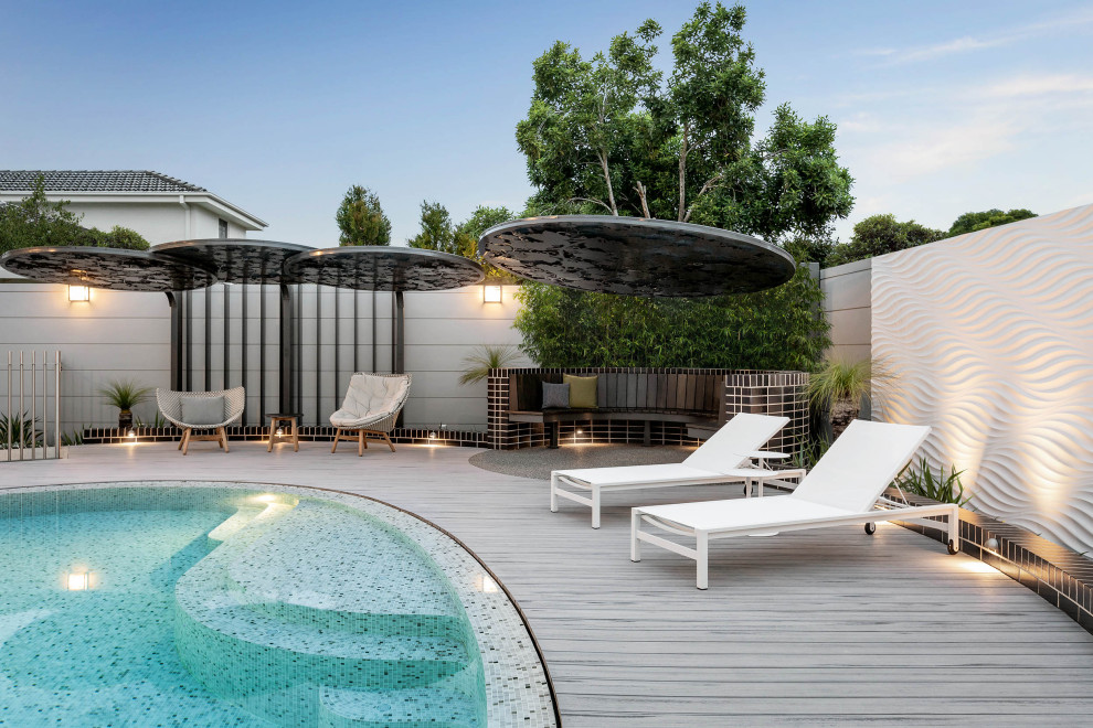 Cette photo montre une piscine tendance sur mesure avec une terrasse en bois.